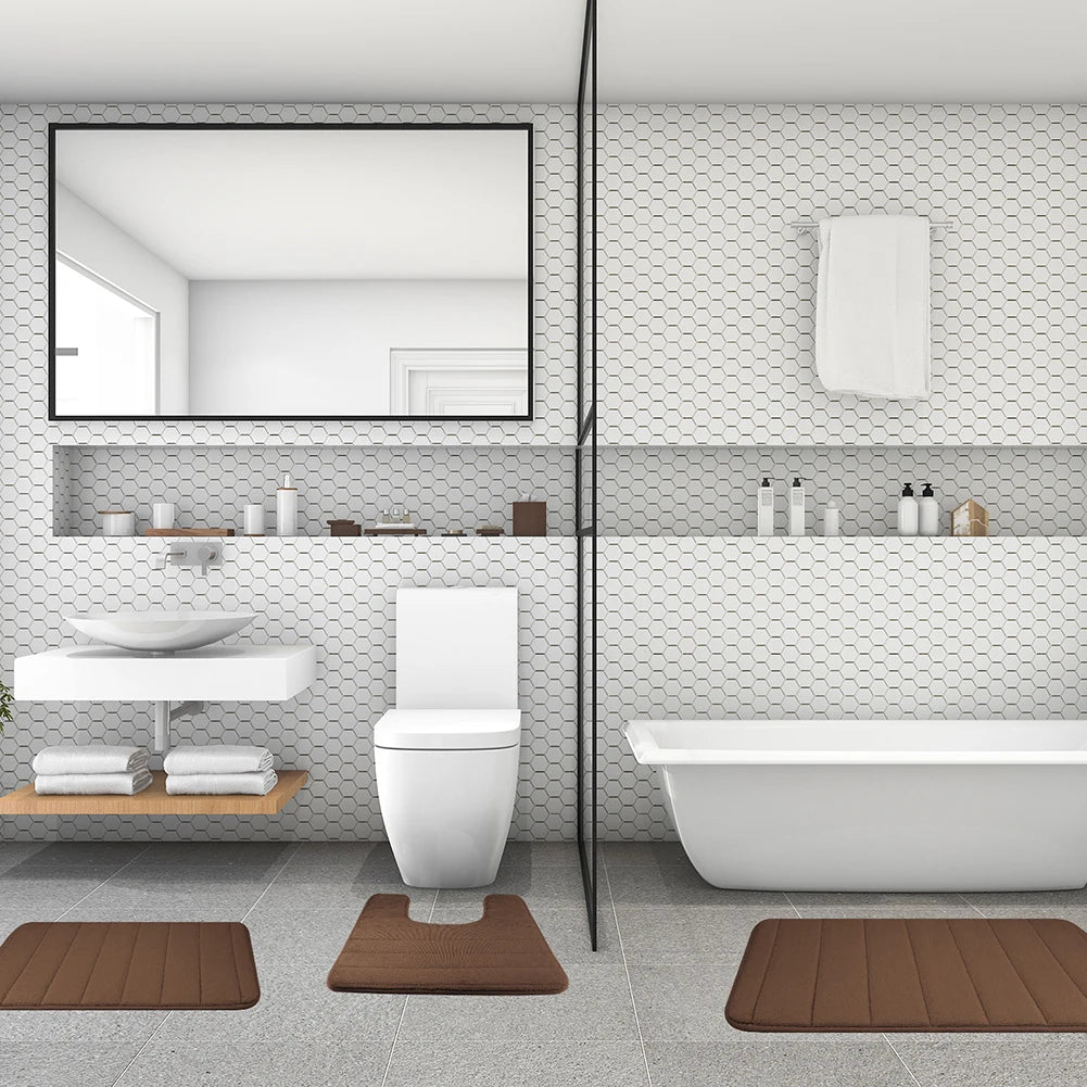 حمام أبيض به مرحاض ومغسلة وحوض استحمام مع ثلاث حصائر إسفنجية بنية.