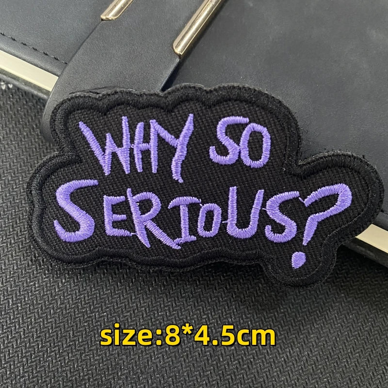 A dark purple embroidered patch shaped like a question mark with the text WHY SO SERIOUS?