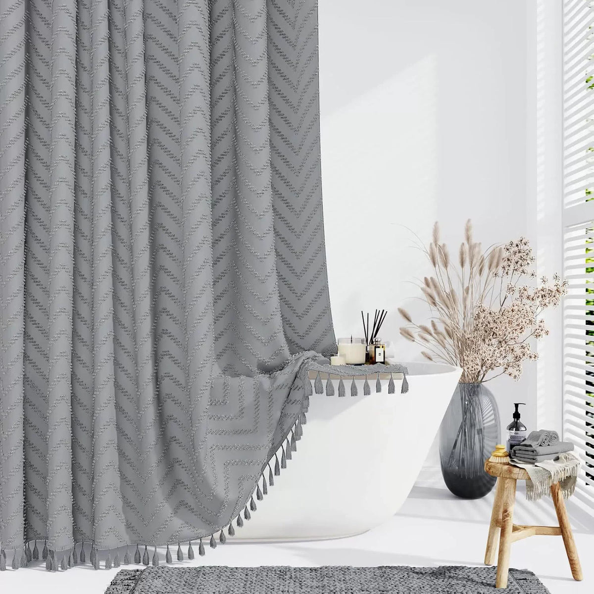Gray boho waterproof shower curtain with tassels and hooks hanging in a bright bathroom