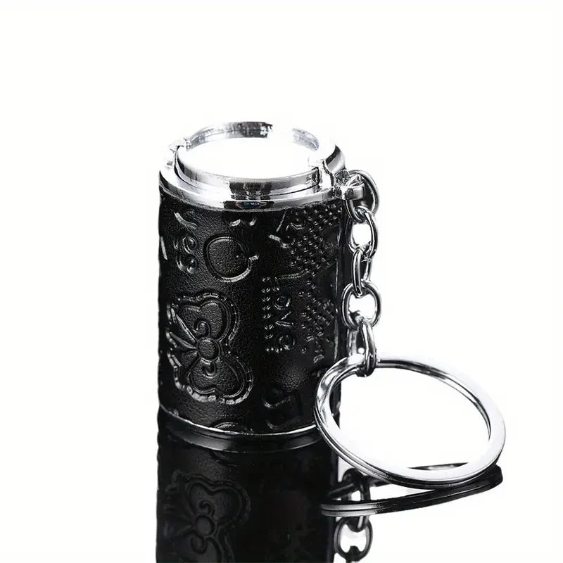 A black metal coin tube keychain with a silver cap and ring attached.