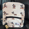 A cream-colored backpack featuring Mickey Mouse graphics and a cow print design.