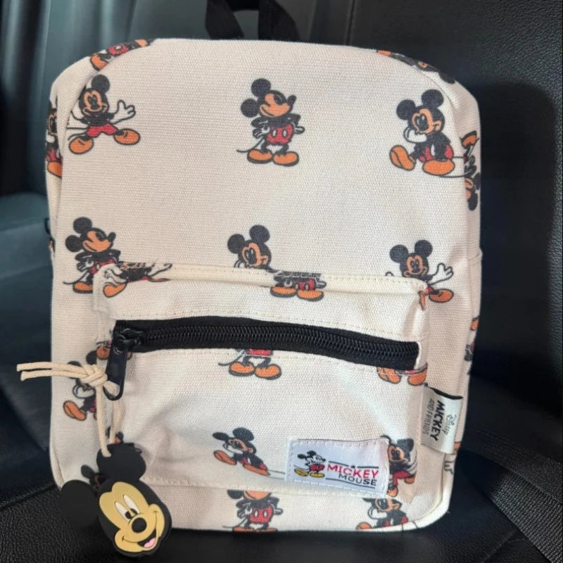 A cream-colored backpack featuring Mickey Mouse graphics and a cow print design.