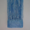 A vertical curtain made of blue and silver metallic tassels hanging against a light gray background.