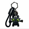 A black Toothless character ornament with glowing green eyes and movable wings attached to a key ring.