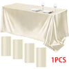 A luxurious satin beige tablecloth draped on a table with silverware and wine glasses set for formal dining.