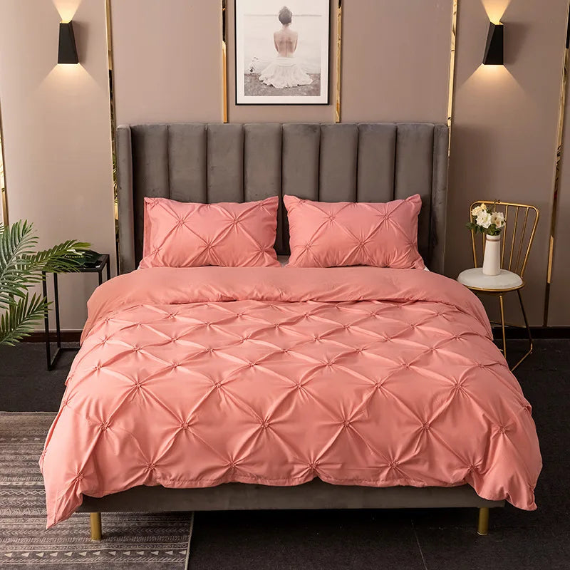 A pink quilted duvet cover set displayed on a bed with a gray headboard and gold accents.