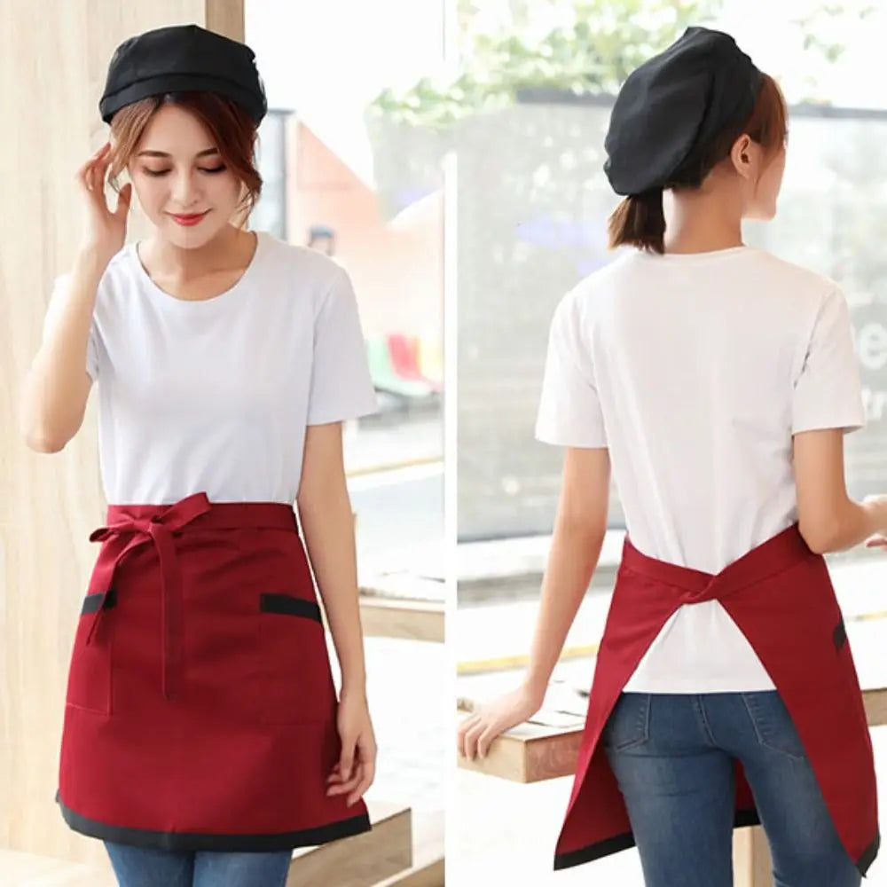 A woman models a classic half apron with pockets in maroon and black on a white t-shirt and jeans.