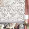 A close-up of a wall featuring a botanical leaf peel-and-stick wallpaper design in black and white on a pale pink background.