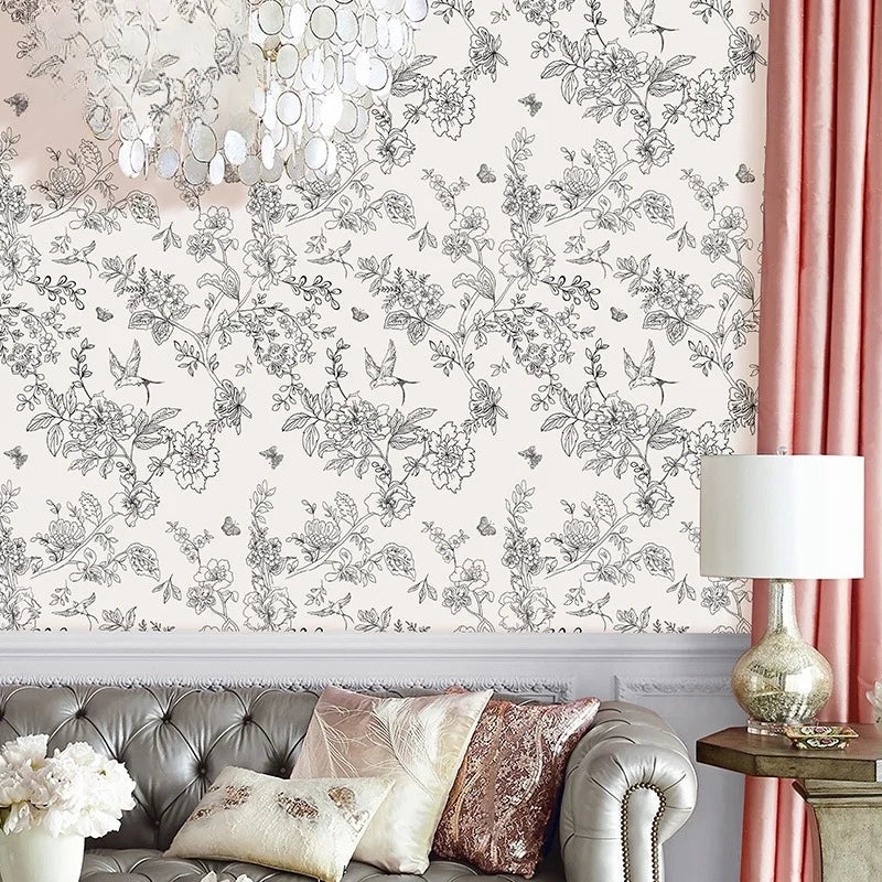 A close-up of a wall featuring a botanical leaf peel-and-stick wallpaper design in black and white on a pale pink background.