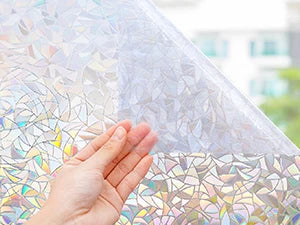 A hand touches a sheet of 3D rainbow privacy window film, showing stained glass decorative vinyl patterns.