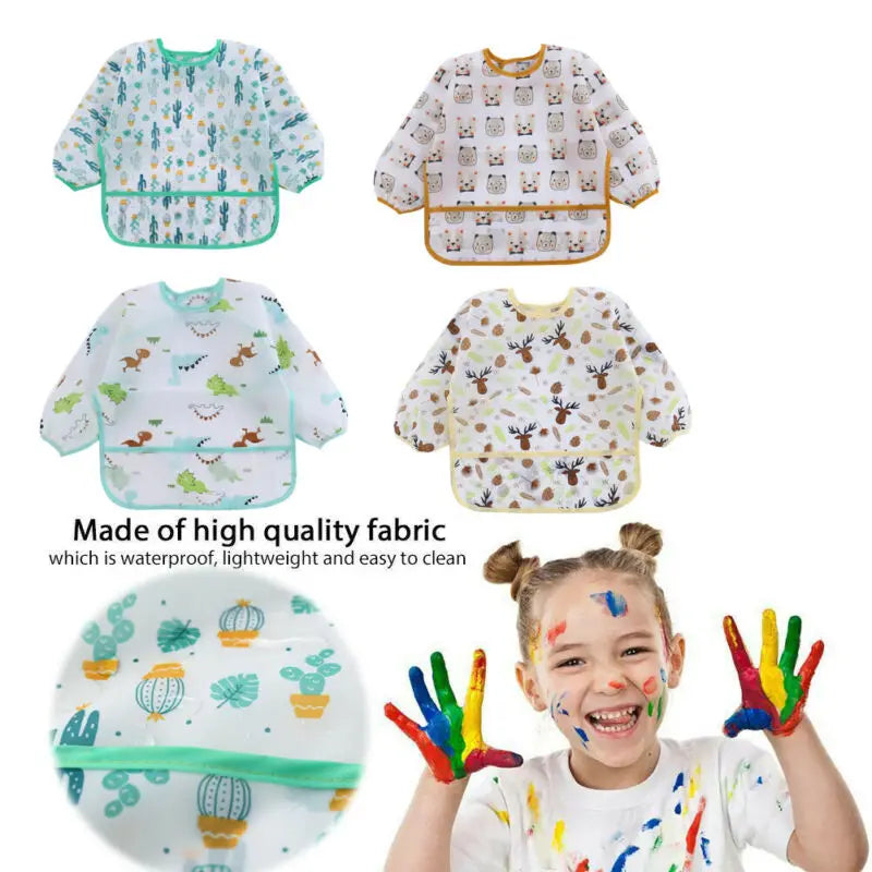 A child is wearing a colorful waterproof long sleeve art smock and feeding bib with various patterns.