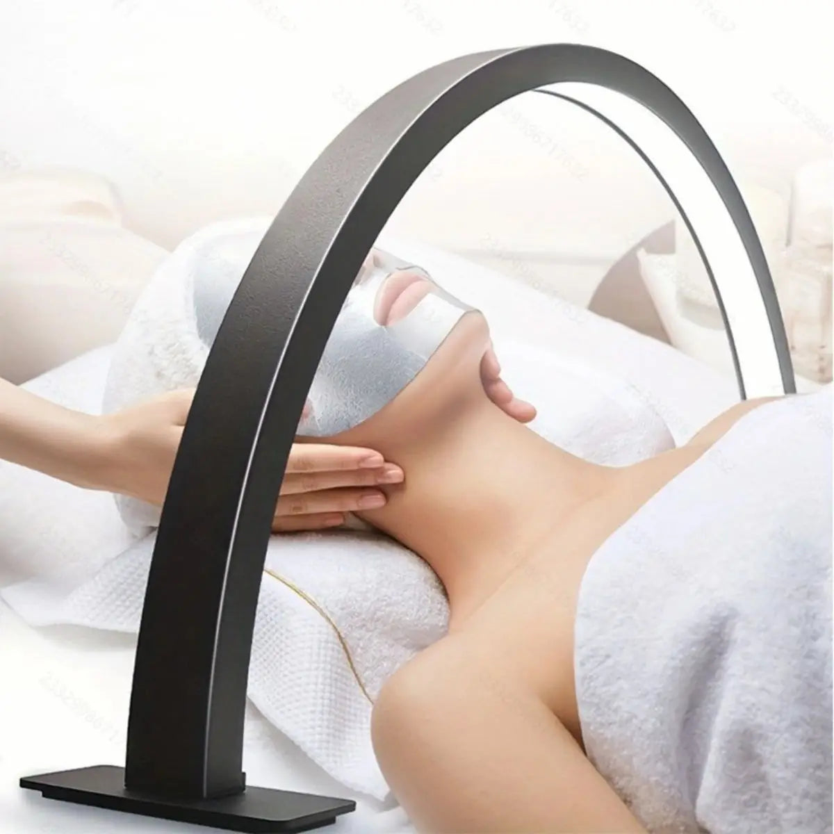 A half-moon LED arc desk lamp is positioned over a woman's face for nail art or lash extension application.