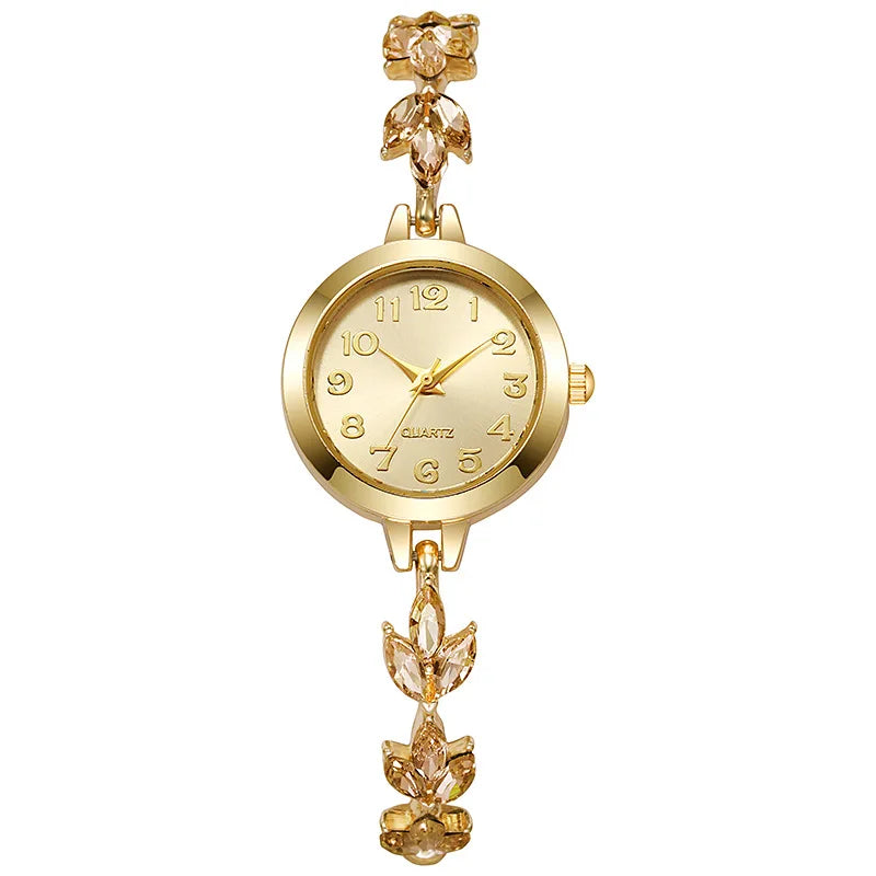 Goldfarbene Uhr mit rundem Zifferblatt und floralen Strassakzenten am Armband.