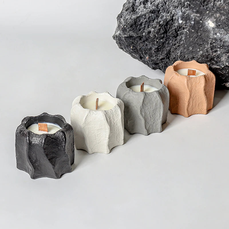 A collection of five candle holders made from textured silicone molds in shades of gray, beige, and black, set against a dark
