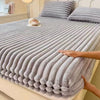 A thick, gray knit fitted bed sheet is draped over a bed, showing its ribbed texture.