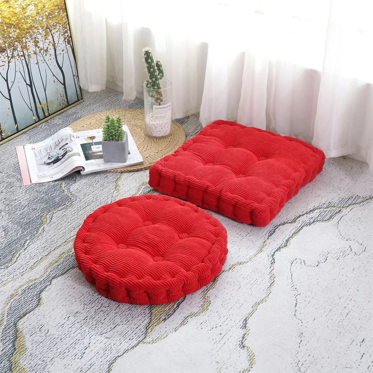 Two bright red corduroy floor cushions are displayed on a light gray rug next to a window.