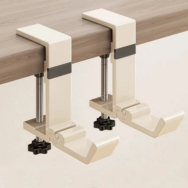 A beige foldable aluminum desk hook designed to hang bags and coats.