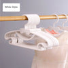 White plastic hangers with bow designs hanging from a wooden rod.