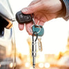 A hand is holding a vintage guitar amplifier wall key holder with a metal key attached, near a car door.