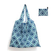A folded reusable shopping tote in blue and teal geometric pattern with an attached carry pouch.