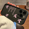 A hand holds a black silicone phone case featuring pink butterfly slogans on the back.