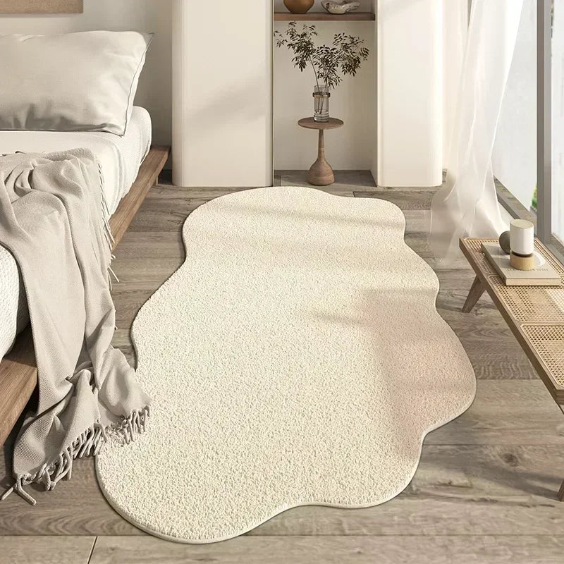 A cream colored irregular area rug with a plush soft texture placed on a light wood floor.