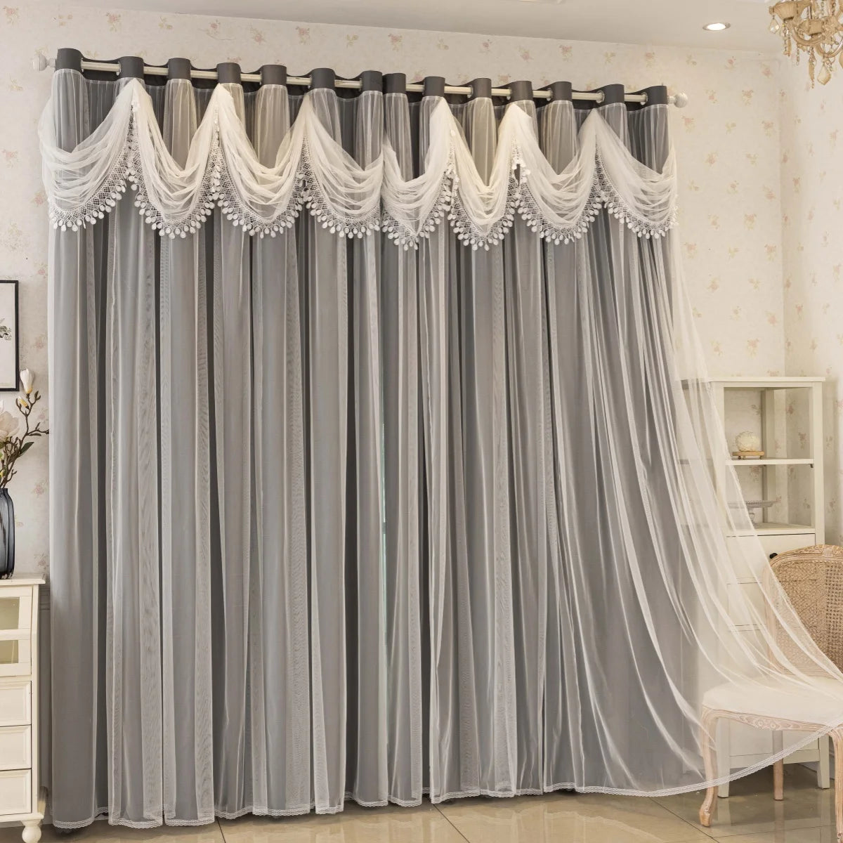 Gray sheer curtains with white lace trim and wave pattern hanging in a window.