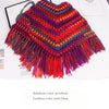 A vibrant rainbow color gradient knitted shawl or garment with fringed edges.