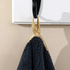 A black towel hanging from a gold-striped hanger against a light background.