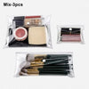 A clear cosmetic bag containing three makeup brushes and a cosmetic tool.