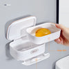 A white double-layer liner design soap dish with a drain rack mounted on a wall for bathroom use.