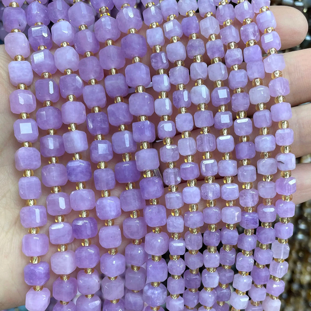 A close-up of purple square faceted beads strung together on a string for jewelry making.