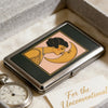 A vintage metal card and cash case featuring an Art Deco design of a woman kissing the moon.