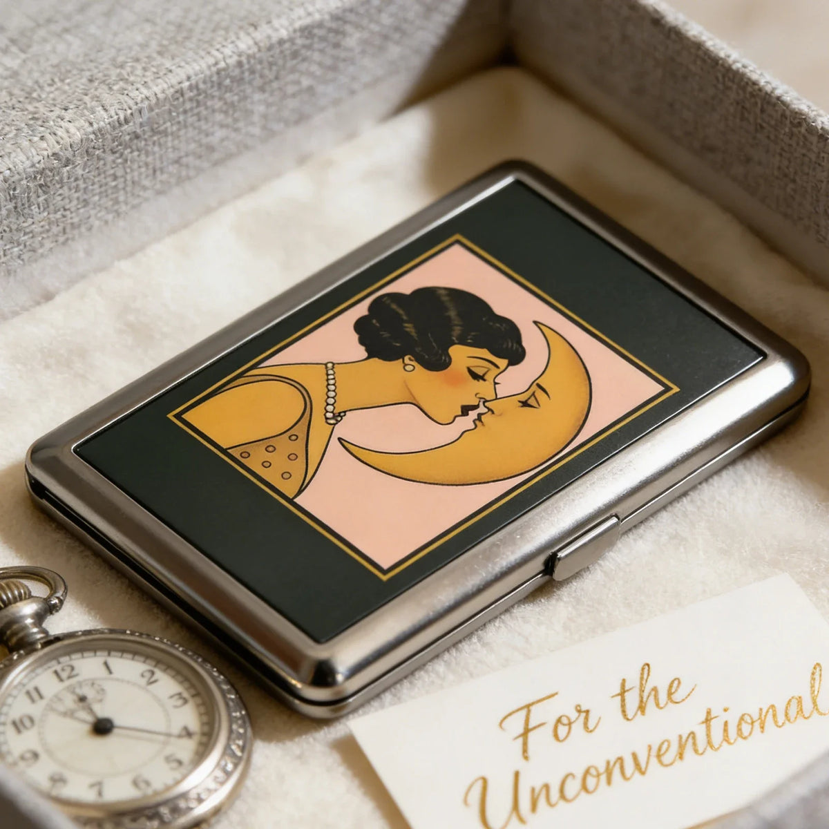 A vintage metal card and cash case featuring an Art Deco design of a woman kissing the moon.