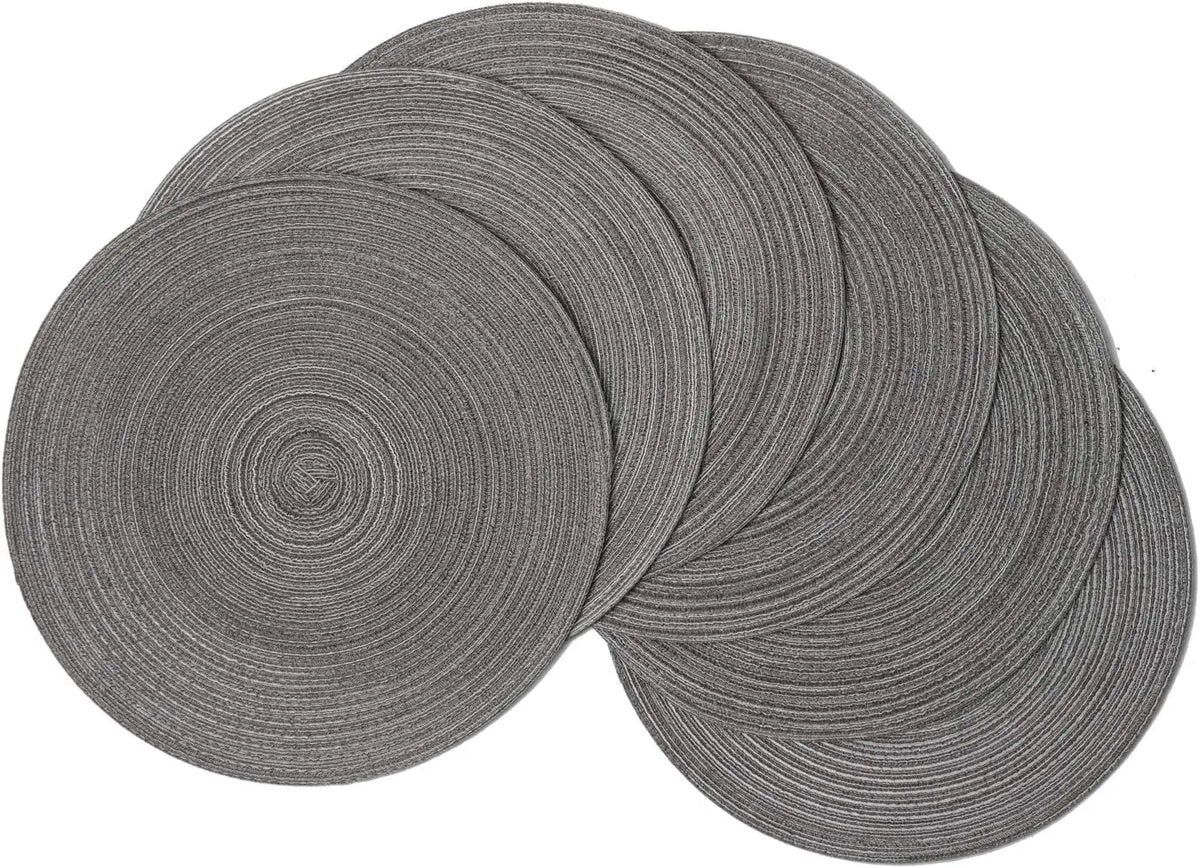 A stack of six gray braided round placemats.