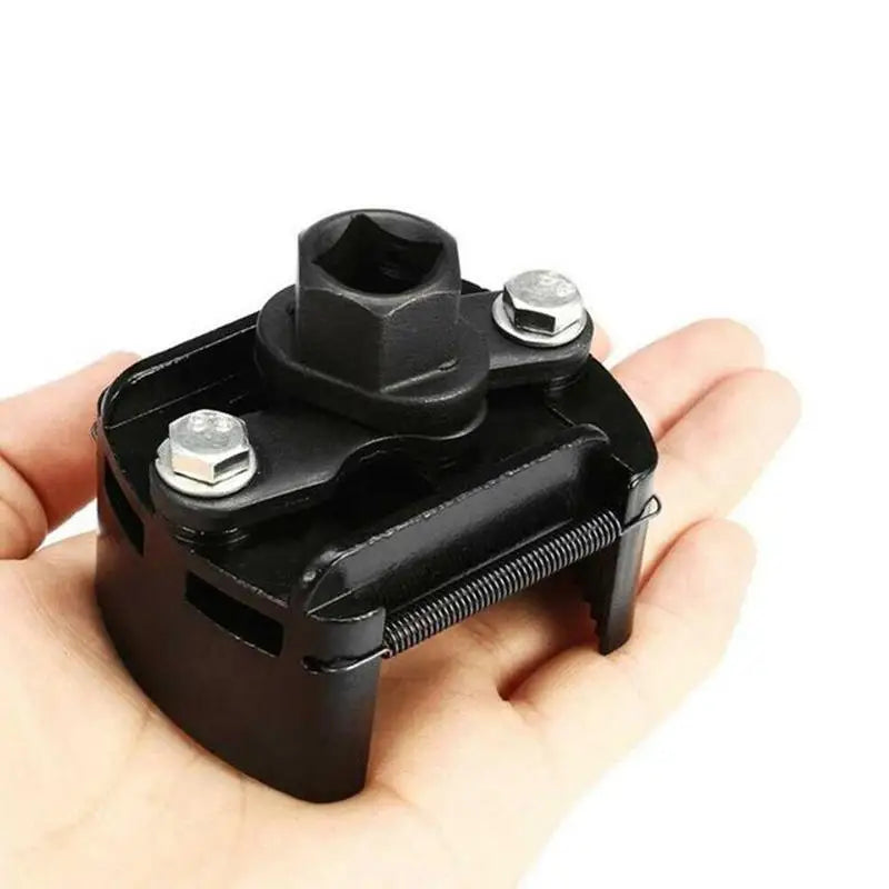 A black adjustable oil filter wrench with a two-jaw design is shown being held in a hand.