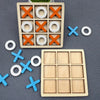 A wooden tic tac toe game set featuring orange and white wooden pieces on a dark gray surface.