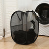 A black foldable laundry hamper with a mesh design is shown next to a white washing machine.