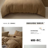 Beige, faltiges Bettbezugsset mit Kissen und kleinem Holztisch auf einem Bett