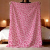 A pink leopard print flannel throw blanket draped over a person's shoulders.