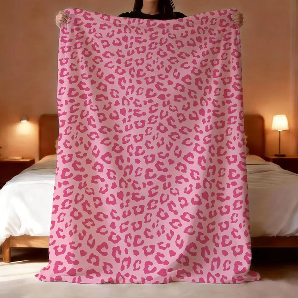 A pink leopard print flannel throw blanket draped over a person's shoulders.