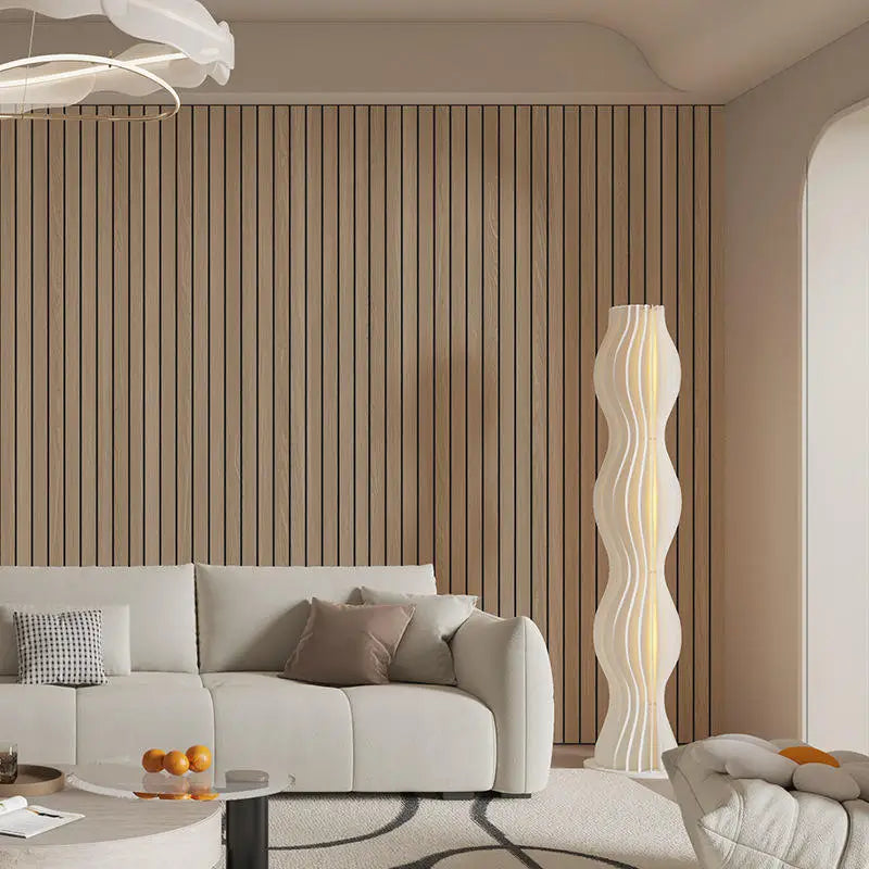 A modern living room featuring a light wood slat wall panel and a tall, sculptural white lamp.