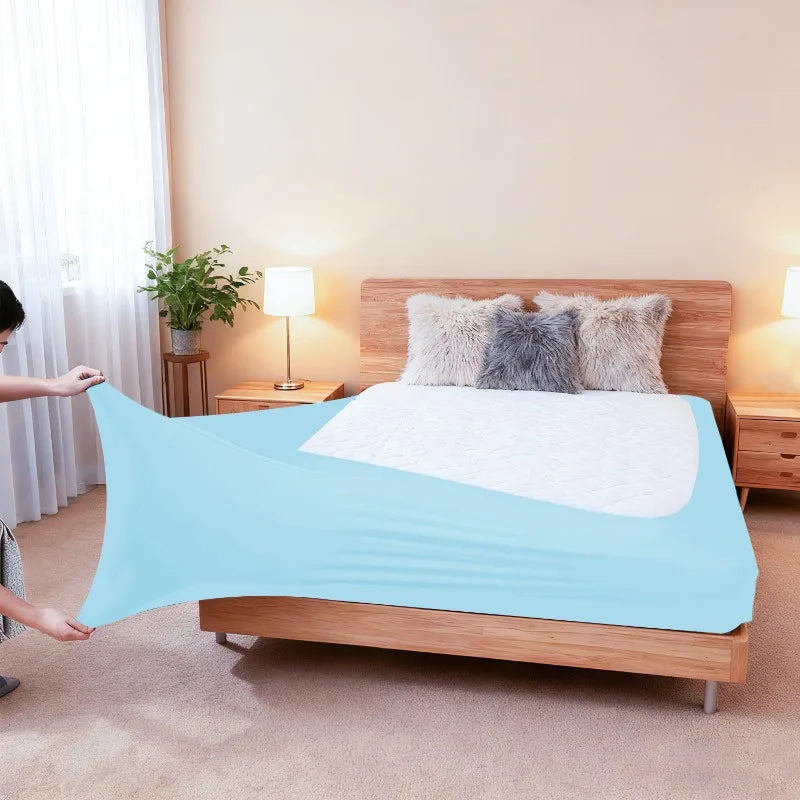 Light blue stretch-fit box spring cover with an elastic edge placed on a wooden bed frame.