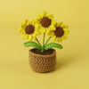 Handcrafted crochet sunflower with yellow petals and brown center growing in a textured pot.