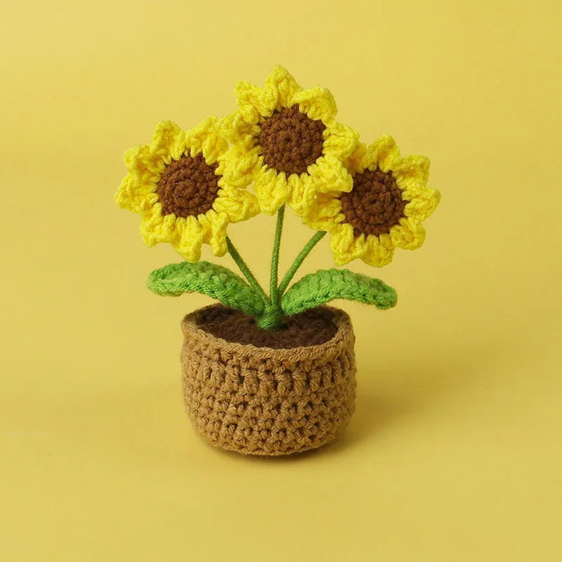 Handcrafted crochet sunflower with yellow petals and brown center growing in a textured pot.