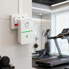 A white energy saver plug with a green lightning bolt is mounted on a white wall in a modern gym setting.