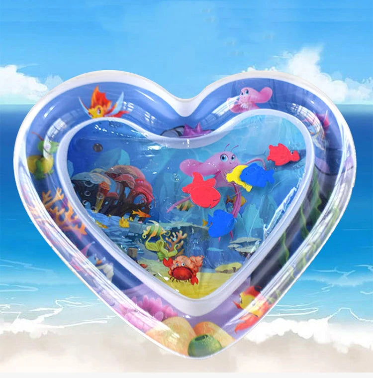 A heart-shaped inflatable water play mat filled with colorful plastic sea creatures for baby sensory development.