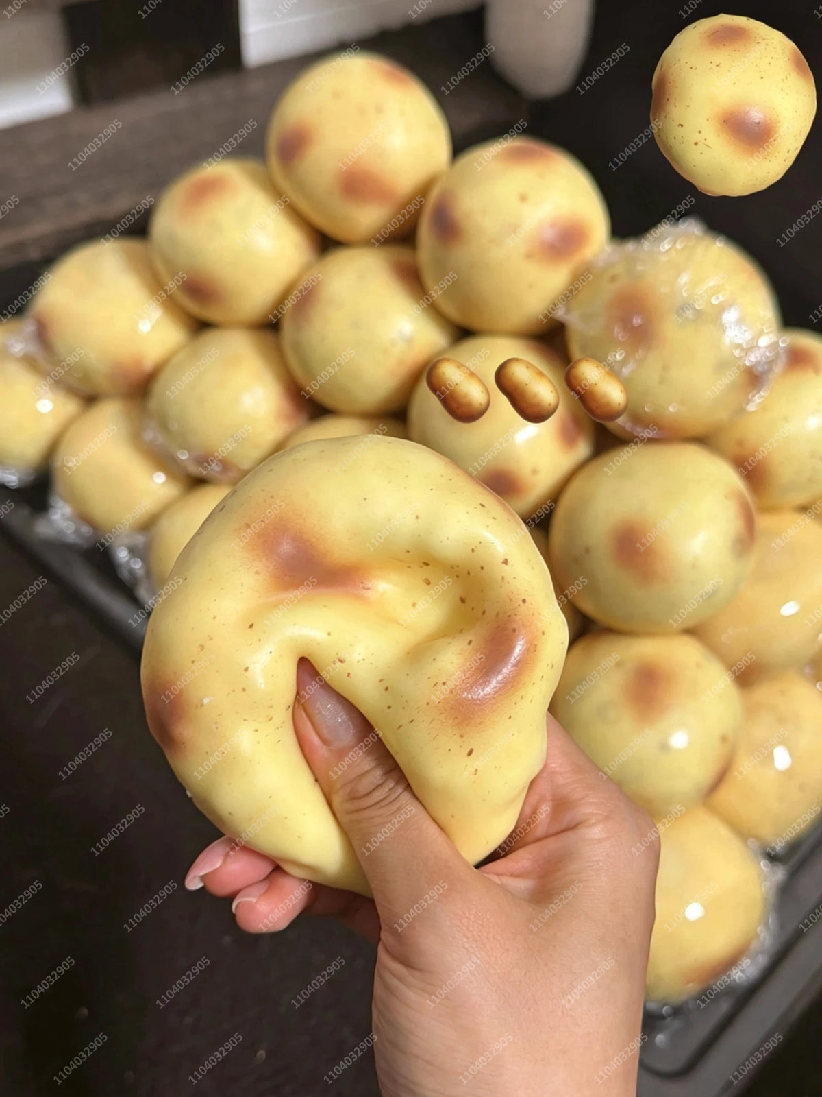 Eine Hand hält einen gelben, ovalen Kartoffel-Stressball-Fidget-Spielzeug, umgeben von vielen ähnlichen Spielzeugen.
