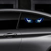 Nahaufnahme eines dunklen Autos mit leuchtend blauen Augen, die durch das Fenster sichtbar sind, und einem Türgriff.