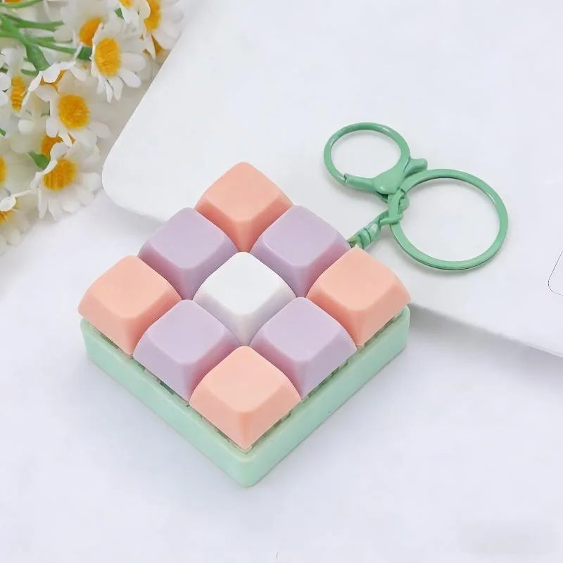 A set of pastel colored silicone cubes and a green keychain fidget toy resting on a white surface.